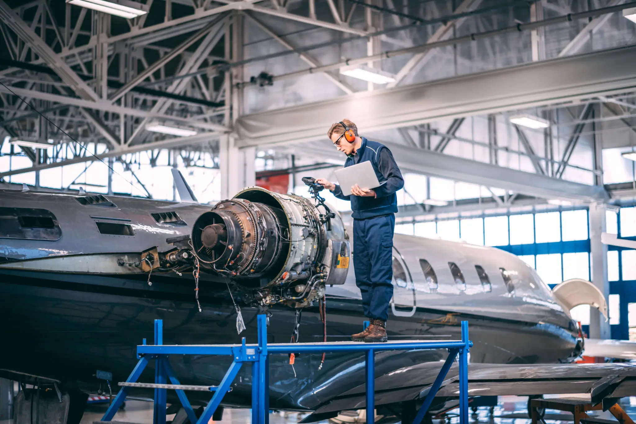Mechanic inspecting aircraft engine in hangar.
